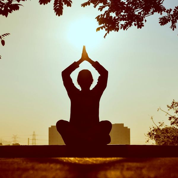 Silhouette of a person meditating peacefully at sunrise.